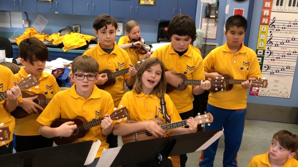 Kids singing holding mini guitars in matching yellow shirts 