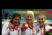 Chelsey holding up her gold medal beside the bronze and silver winners