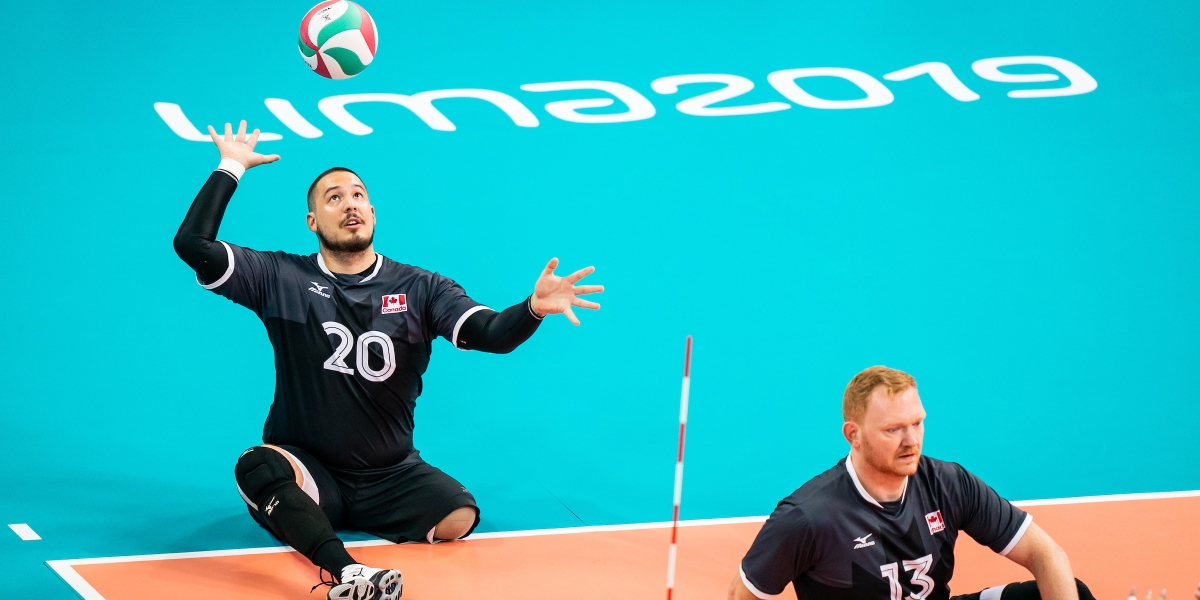Jesse Buckingham serves in a game of sitting volleyball
