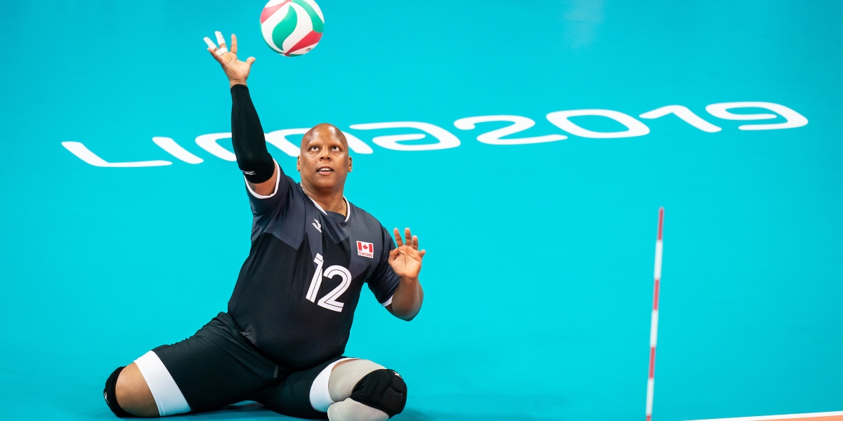 Jamoi Anderson serves in a game of sitting volleyball