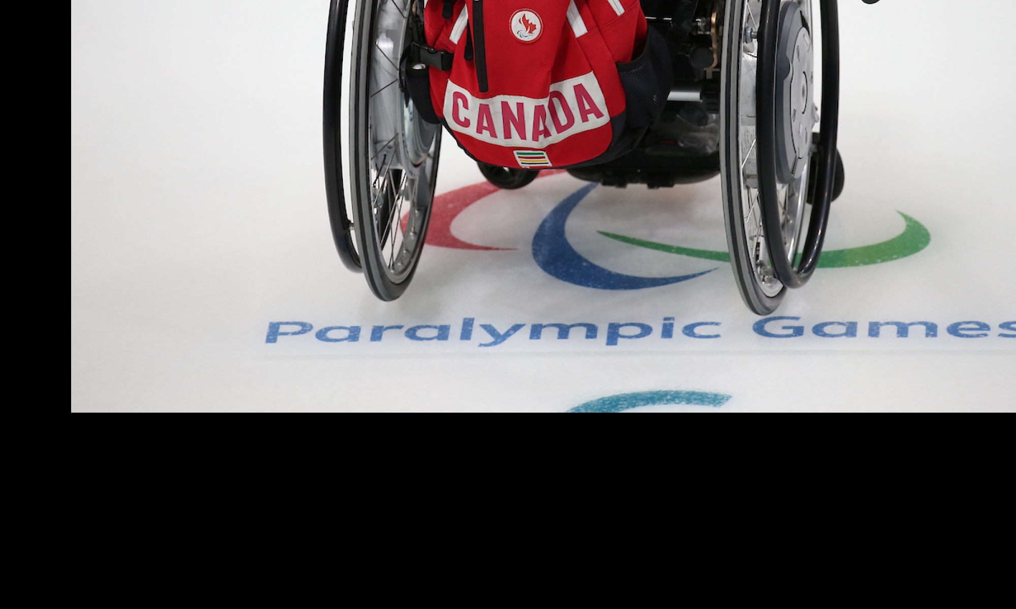 Wheelchair on curling ice with a team canada backpack