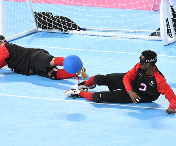 Goalball team stopping the ball from going into the net, players are laying down 