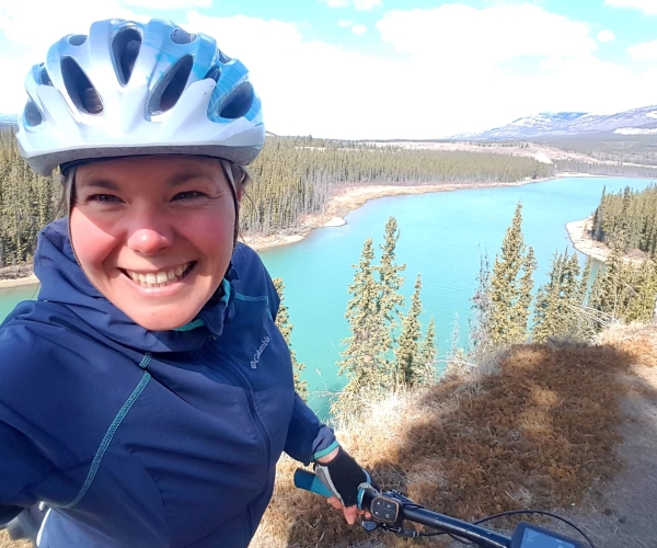 Stephanie Dixon on her bike in front of a lake in the Yukon. 