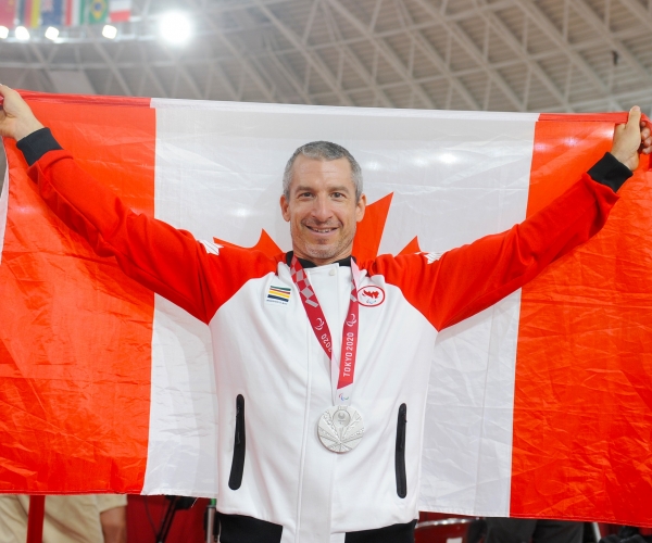 Tristen Chernove wearing his silver medal and holding a Canadian flag at Tokyo 2020. 