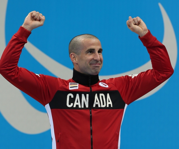 Benoit Huot with his arms in the air celebrating on the podium. 