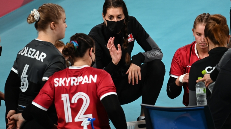 Head coach Nicole Ban kneeling down talking to the Canadian women's sitting volleyball team on the sidelines at the Tokyo 2020 Paralympic Games