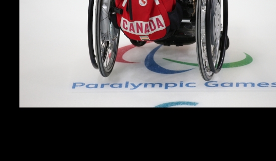 Wheelchair on curling ice with a team canada backpack