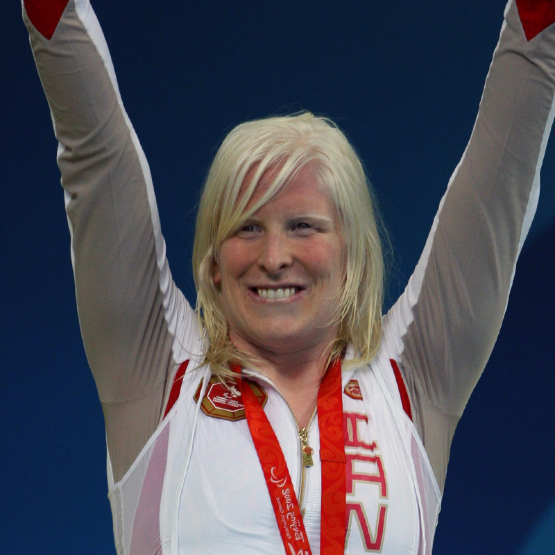 La paralympienne canadienne Chelsey Gotell célèbre sur le podium, les bras levés, portant sa médaille et le survêtement de l’équipe canadienne aux Jeux paralympiques.