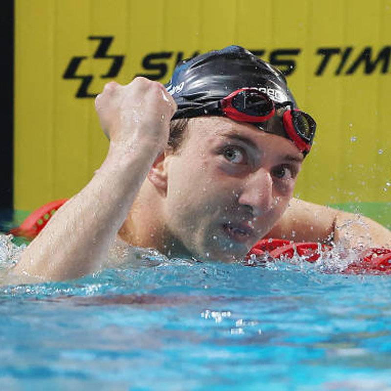 Le nageur paralympique canadien Alec Elliot lève le poing en l'air en se reposant sur une corde de ligne après une course de natation.