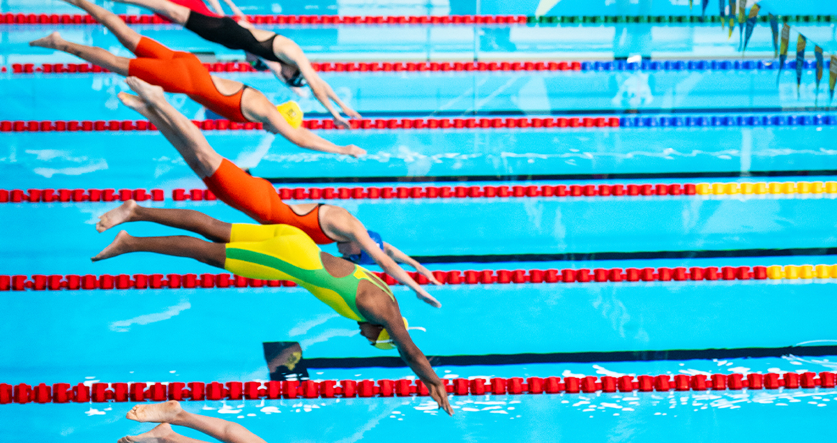 Swimmers diving into a pool at the Santiago 2023 Parapan American Games. | Nageurs plongeant dans une piscine lors des Jeux parapanaméricains de Santiago 2023.