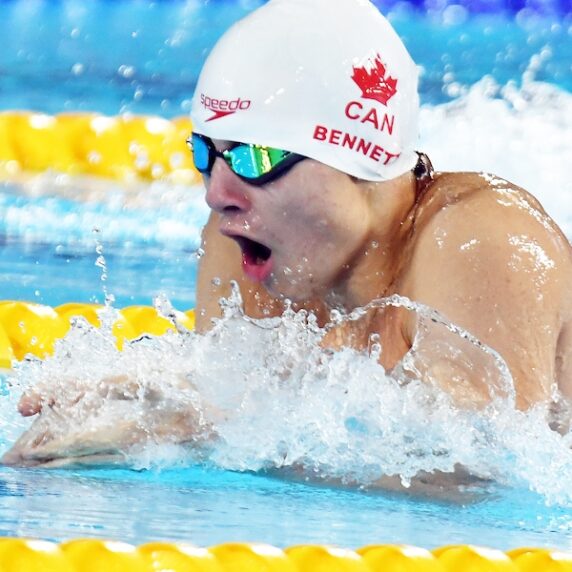 Canadian Para swimmer Nicholas Bennett competing in a breaststroke swimming race as he emerges from the water taking a breath before going into his stroke.