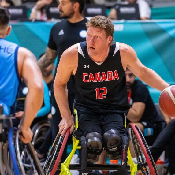 La star du basket-ball en fauteuil roulant Patrick Anderson fait rebondir le ballon.