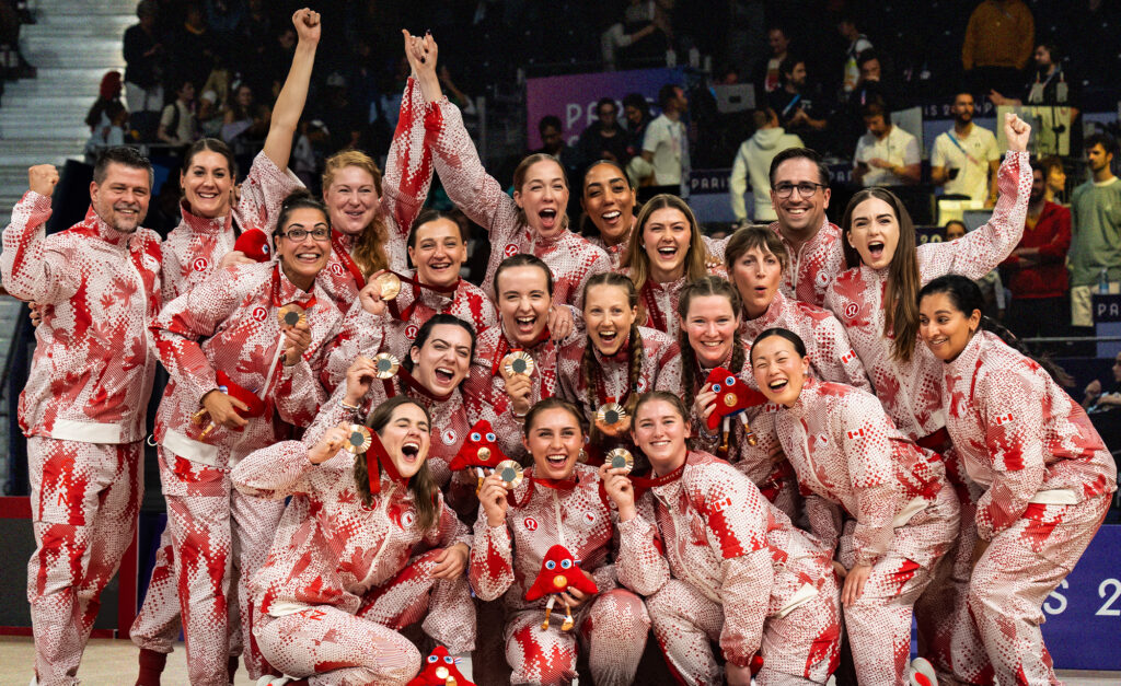 L’équipe féminine canadienne de volley-ball assis célèbre sa médaille de bronze aux Jeux paralympiques de Paris 2024. L’équipe pose ensemble dans ses uniformes à motifs rouges et blancs, souriant et tenant fièrement leurs médailles de bronze et les mascottes des Jeux paralympiques. Leur joie et leur unité reflètent cet accomplissement remarquable sur la scène mondiale.