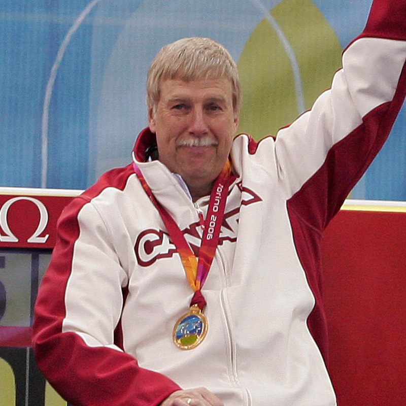 Gary Cormack, curleur en fauteuil roulant canadien, portant une médaille d'or et une veste de l'équipe du Canada, levant le bras en signe de célébration.