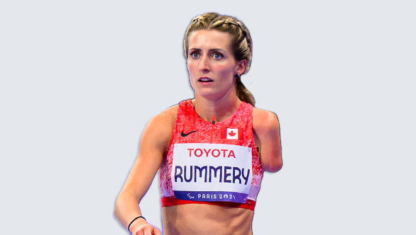 La Paralympienne canadienne Amanda Rummery, sprinteuse en para-athlétisme, portant un uniforme rouge et blanc d'Équipe Canada avec un dossard de compétition affichant 'Rummery' et 'Paris 2024'. Elle arbore une expression concentrée, ses cheveux blonds attachés en tresse, et son bras gauche est amputé sous l'épaule.