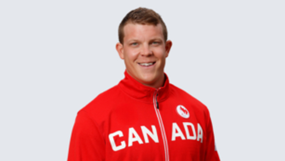 Le Paralympien canadien Jeremy Hall, rameur en para-aviron, portant une veste rouge d'Équipe Canada avec 'CANADA' en lettres blanches sur la poitrine et le logo paralympique canadien sur le côté gauche. Il sourit avec assurance et regarde directement la caméra