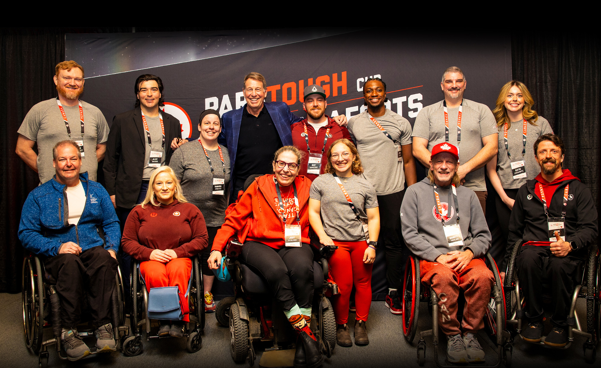 Photo de groupe de paralympiens canadiens, d’ambassadeurs du parasport et de l’animateur de CBC Scott Russell lors de l’événement de collecte de fonds ParaTough Cup à Toronto. Le groupe pose en souriant devant une bannière noire portant le logo de l’événement, célébrant le sport et l’impact communautaire.