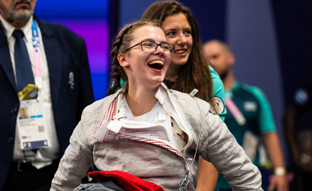 Trinity Lowthian, escrimeuse canadienne en fauteuil roulant, concentrée lors d’une compétition, vêtue de sa veste d’escrime et de lunettes. Représentante fière du Canada aux Jeux paralympiques de Paris 2024.