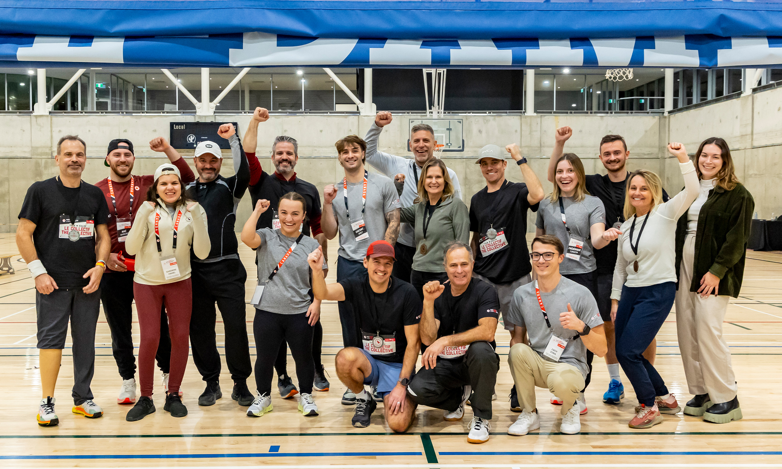 Un groupe de participants et de bénévoles souriants posent ensemble dans un gymnase, le poing levé, après avoir participé à l’événement ParaTough Cup à Montréal, célébrant leur soutien au parasport au Canada.