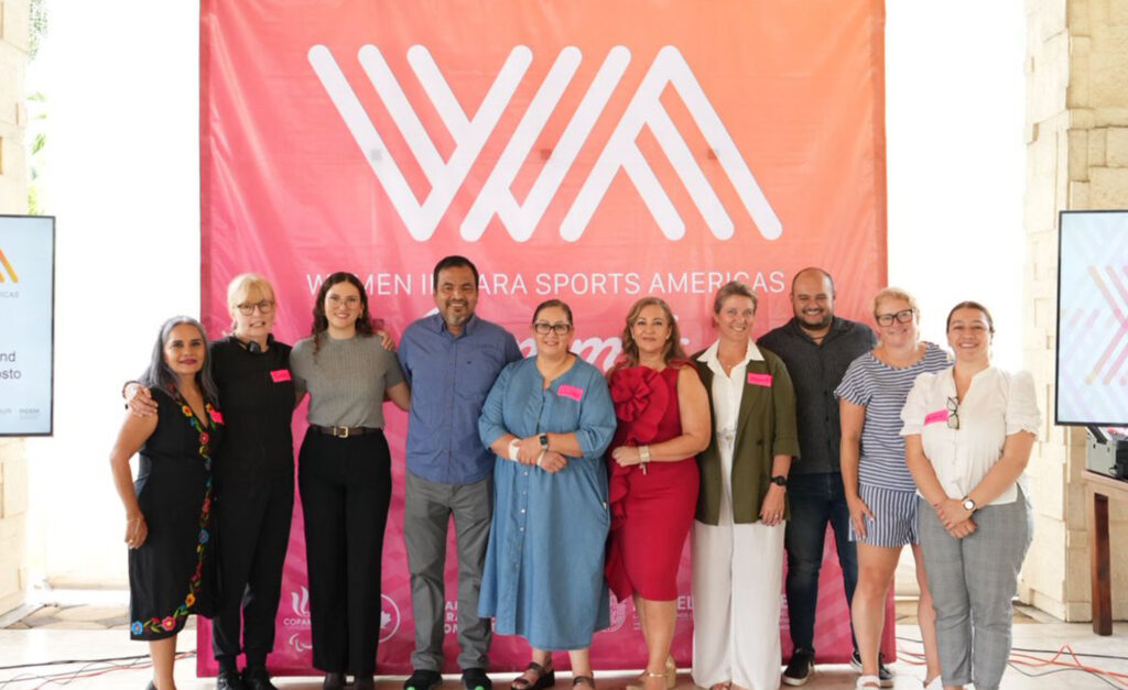 Photo de groupe des conférenciers et organisateurs devant une grande bannière rose et orange indiquant « Women in Para Sports Americas », lors du Sommet 2025 des femmes dans le sport paralympique des Amériques.