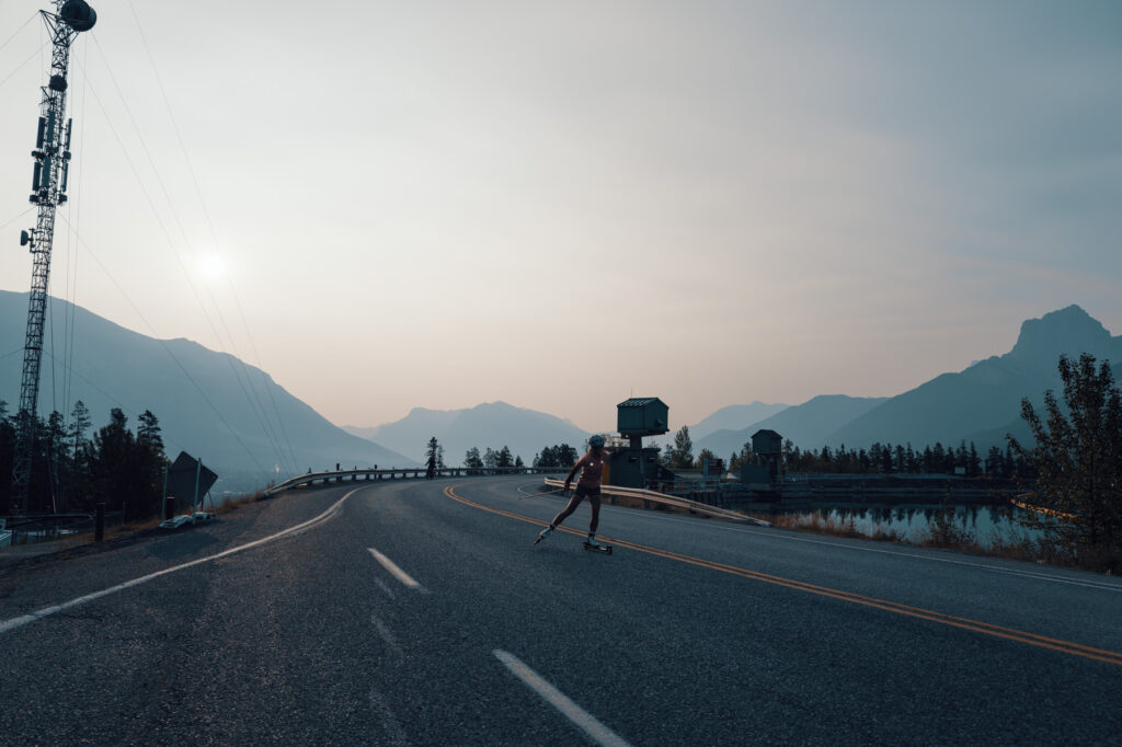 Brittany Hudak roller skis in Canmore against a sunrise sky