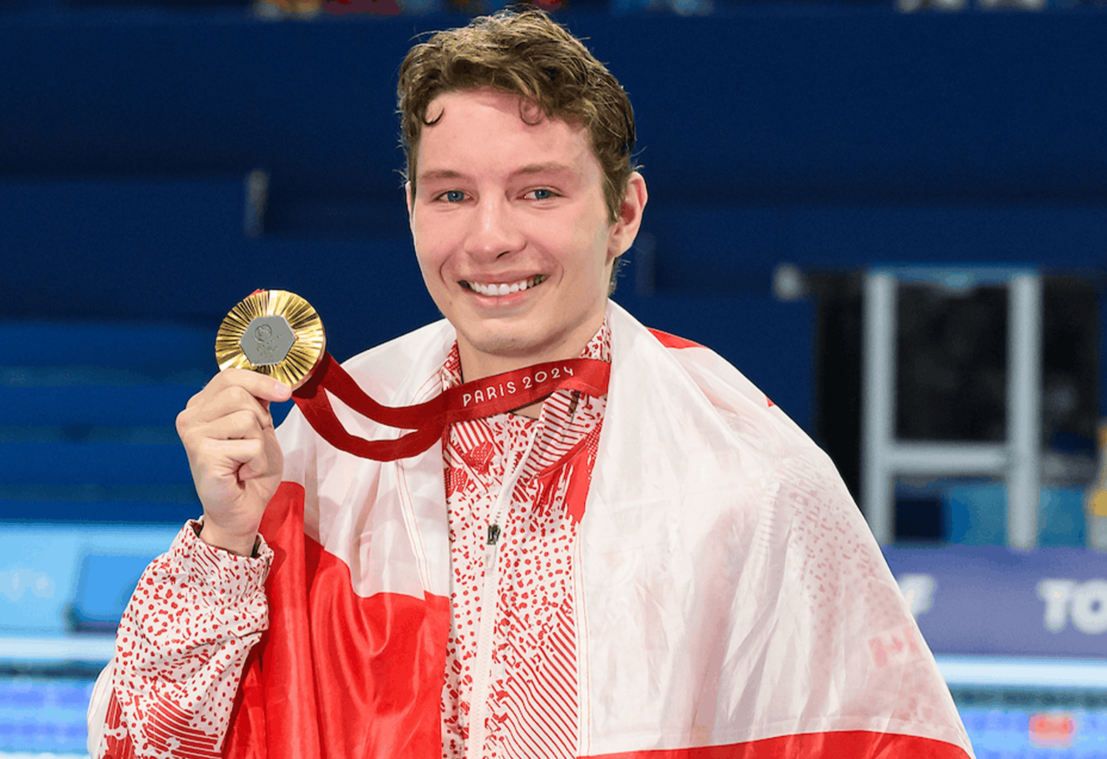 Nick Bennett, nageur posant avec une médaille et un drapeau autour des épaules